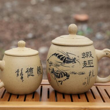 Pair of traditional Japanese clay teapots with painted designs on a wooden tray.