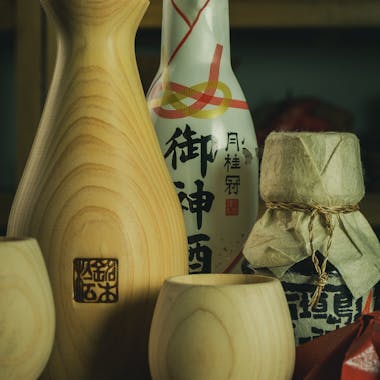 Traditional Japanese sake vessels and bottles on wooden table. Perfect for cultural and culinary themes.