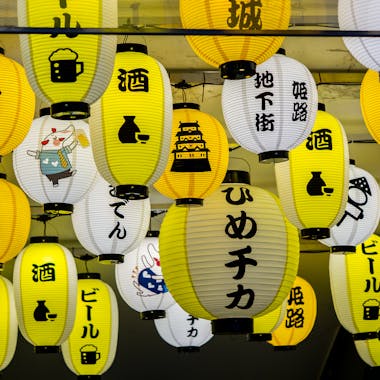 Vibrant Japanese paper lanterns with Kanji characters hanging at night.